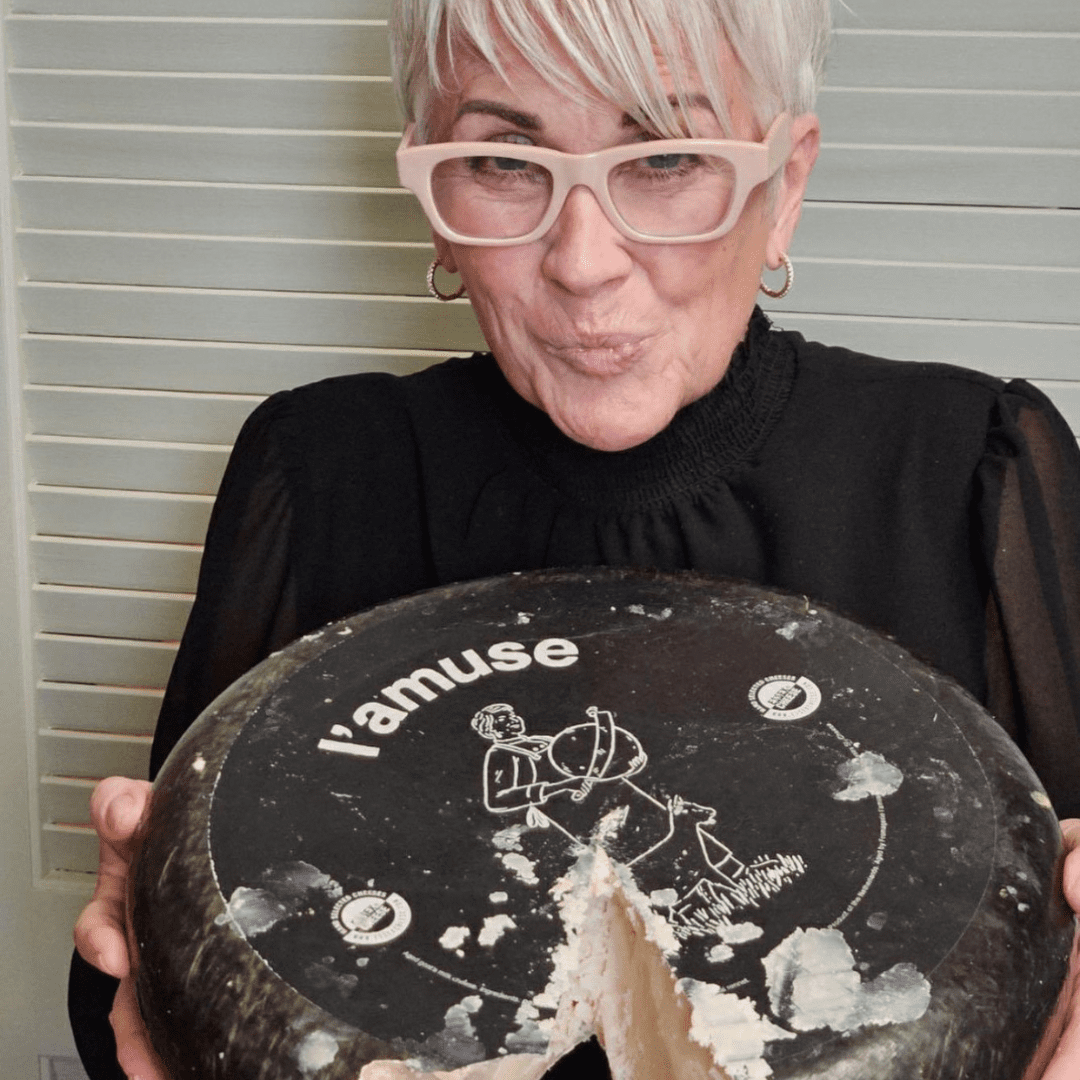 Woman presenting large cheese wheel